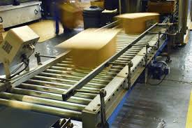 Cardboard packaging boxes travelling down a conveyor belt at a high rate of speed. MIS software for Packaging manages your machines