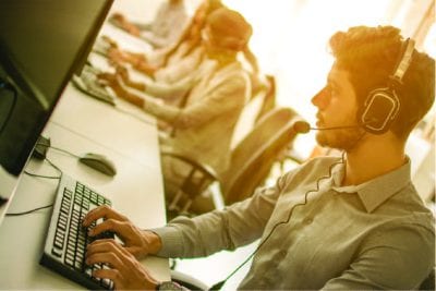 Man sitting at a computer wearing a headset.