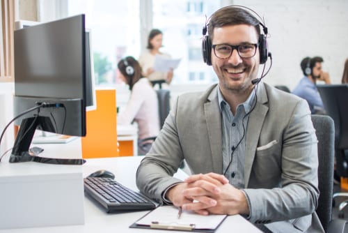 Smiling customer experience rep sits in front of computer to highlight how digital transformation and the internet has revolutionized customer care